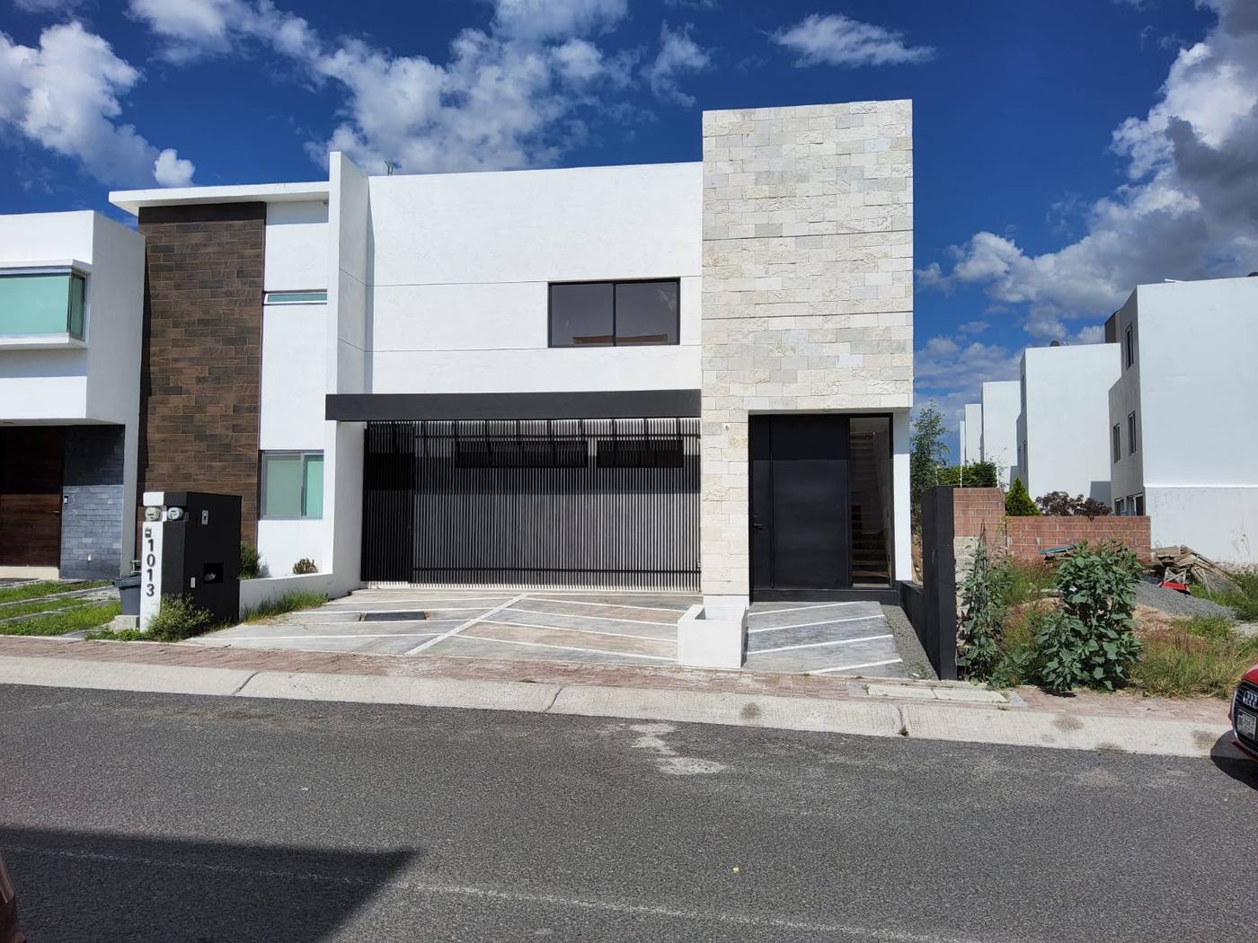 Casa residencial llave en mano en Querétaro: interior con travertino, cocina en granito negro y escalera flotante de madera — AVives Arquitectos